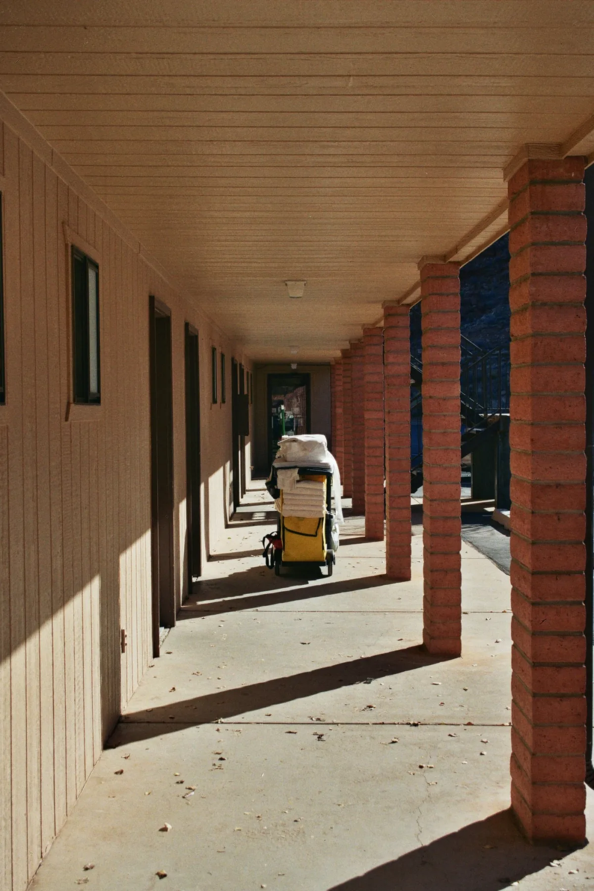 A sunlit exterior corridor with repeating brick columns.