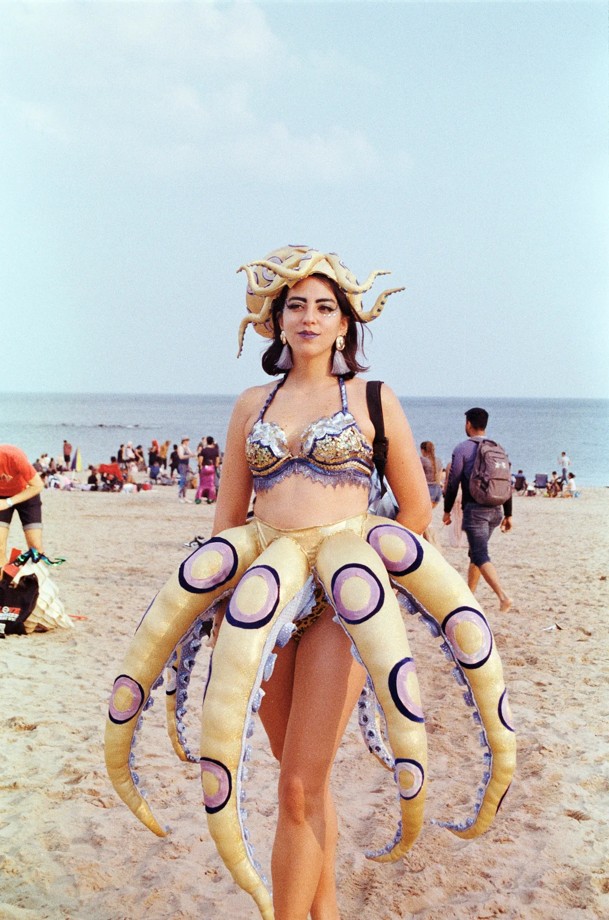 A person in an octopus costume on the beach.